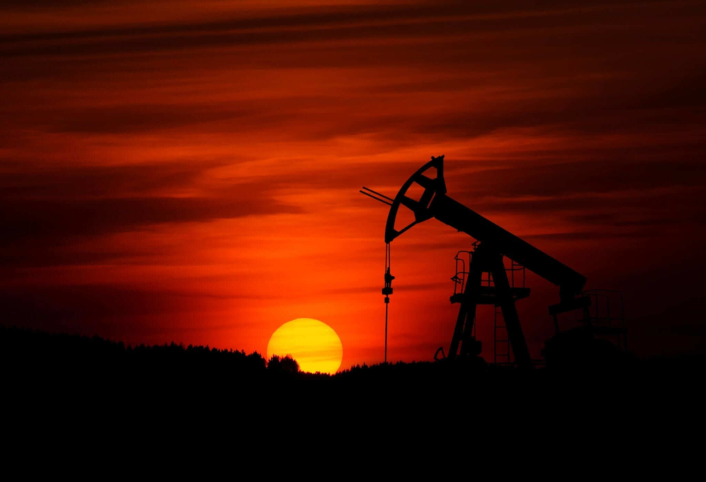 A vibrant red sunset with a silhouette of an oil rig