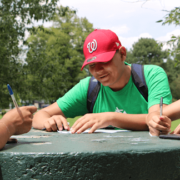 Three youth Promotorxs write on an outdoor table
