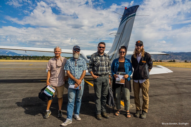 Five people stand in front of a small plane, gearing up for an EcoFlight.