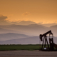 Oil and gas pump jack in front of mountain landscape