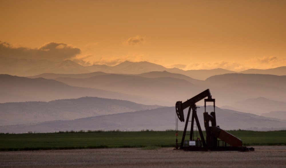 Oil and gas pump jack in front of mountain landscape