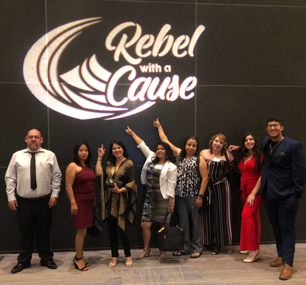Eight Promotores stand with sign at the Rebel with a Cause Gala