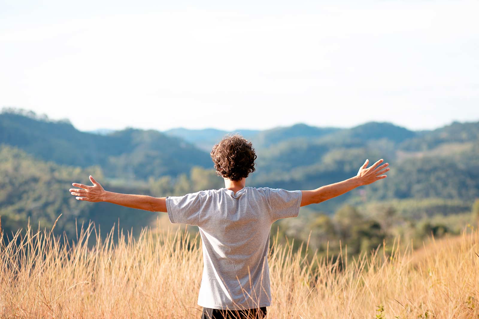 Photo of man holding arms out wide in nature