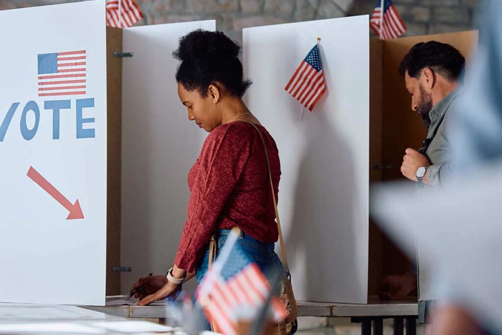 Photograph of woman at voting booth with American flags