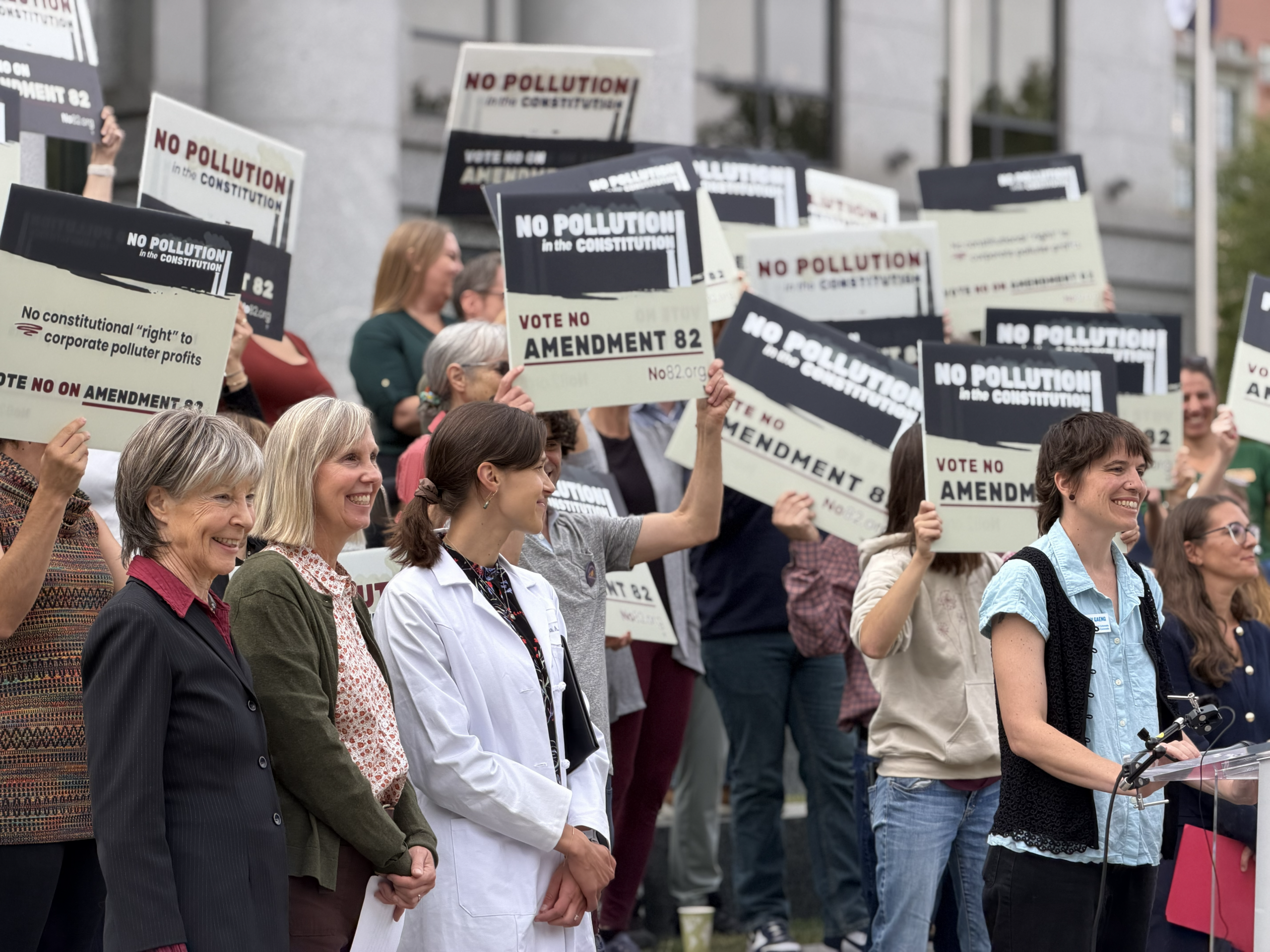 People gather outside the Colorado Supreme Court at a press conference opposing Amendment 82, with doctors, attorneys, and activists speaking to the crowd.